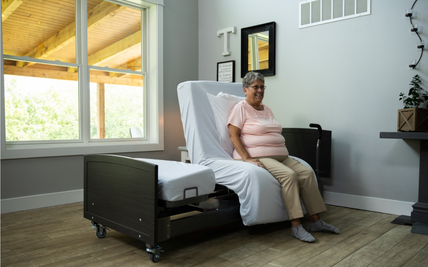 Image of a woman sitting on the ActiveCare Fixed Height Hospital Bed.