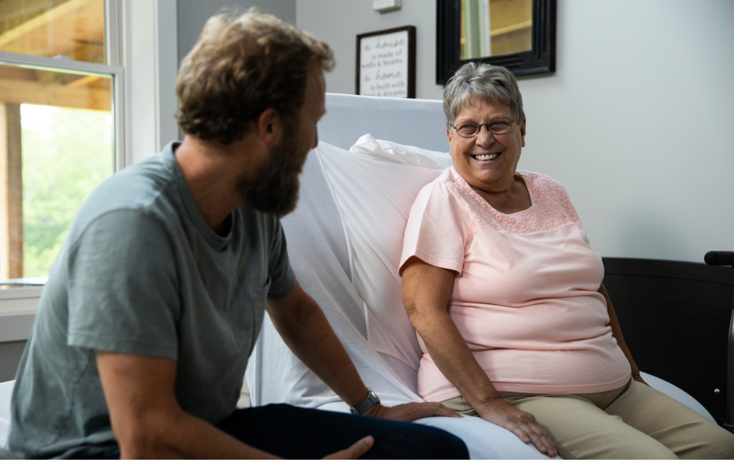 ActiveCare Fixed Height Hospital Bed 5 Image of woman and man chatting while sitting on ActiveCare Hospital Bed.