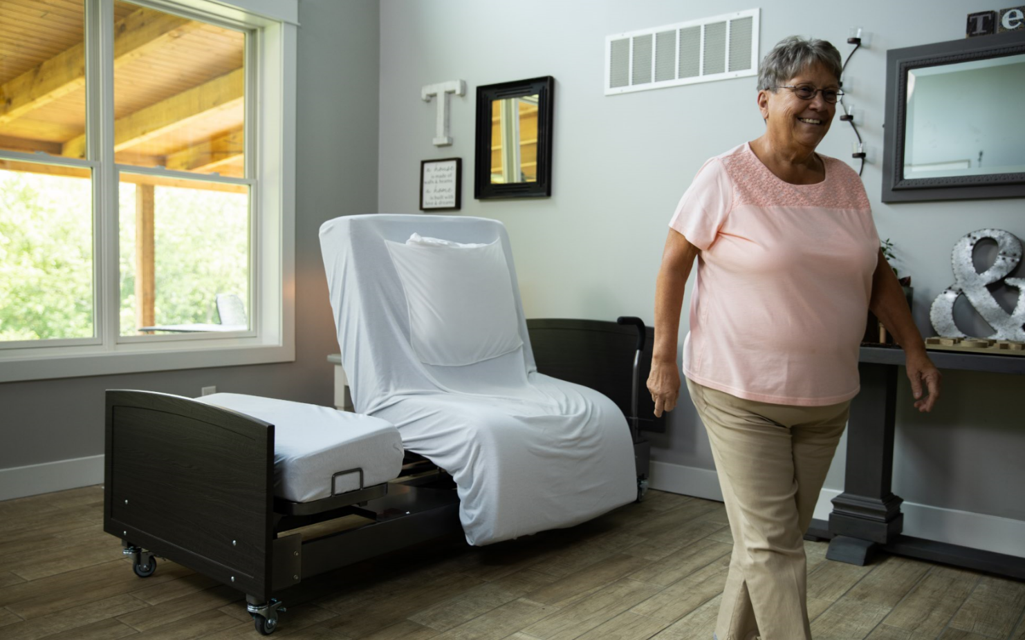 Image of the ActiveCare Fixed Height Bed and woman walking away from it.