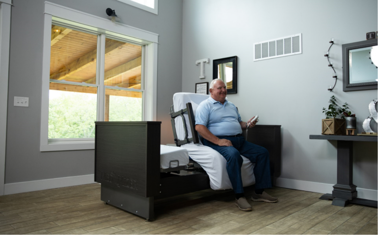 Image of ActiveCare Deluxe Hospital Bed with man sitting down on it.