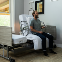 Image of man sitting in bedroom on the ActiveCare hospital bed that's rotated. thumbnail
