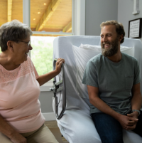 Image of man and woman sitting on the ActiveCare hospital bed chatting. thumbnail