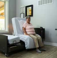 Image of a woman sitting on the ActiveCare Fixed Height Hospital Bed. thumbnail